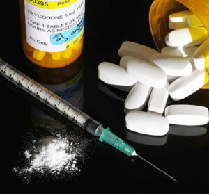 syringe with needle and white powder representing opioid drug epidemic